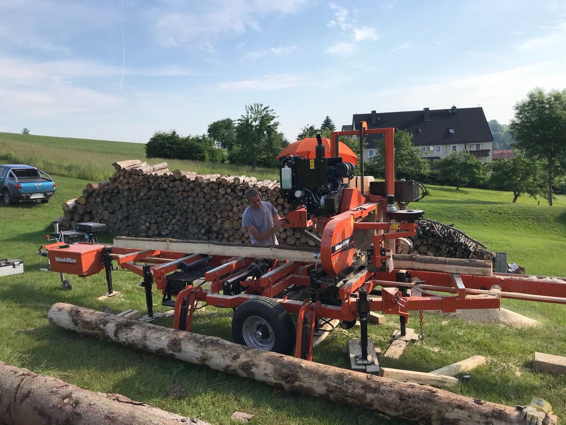Mobiles Sägewerk auf einer Wiese mit Holzstapel